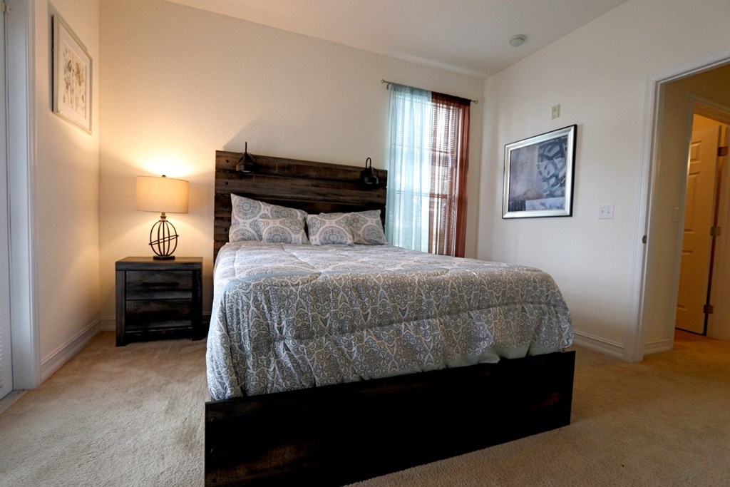 A bedroom with a bed, nightstand, and lamp.