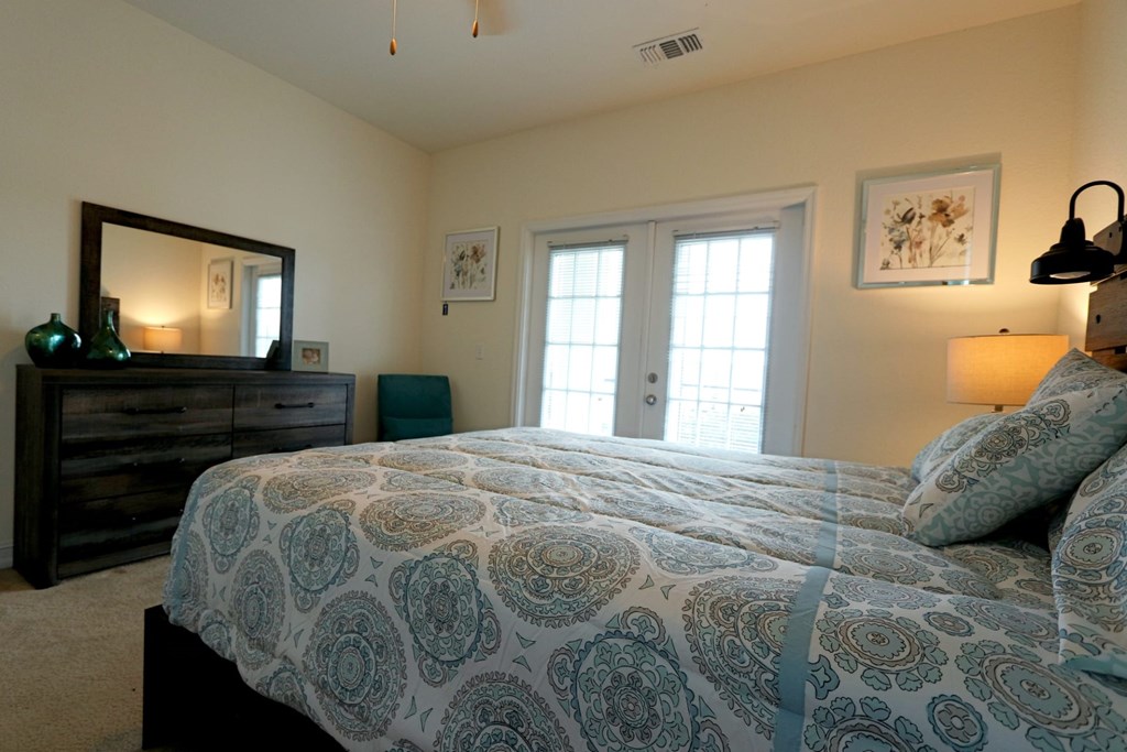 A bedroom with a bed, dresser, and mirror.