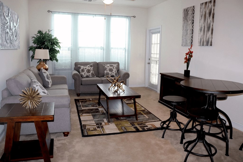 A living room with a grey couch, a coffee table, and a black piano.