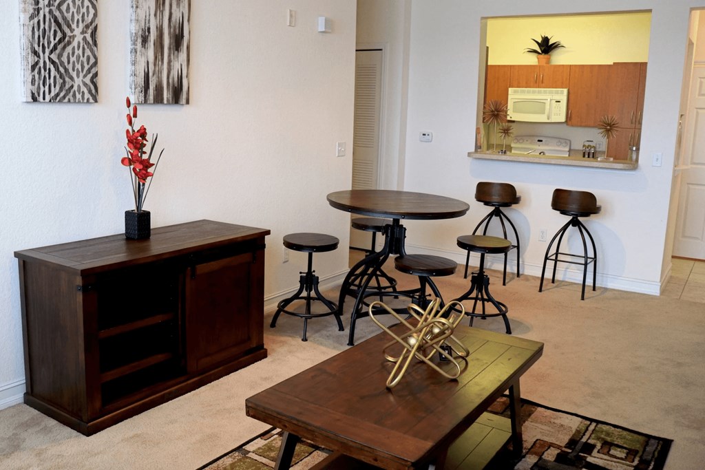 A room with a wooden cabinet, a table with a vase of flowers, and a mirror on the wall.