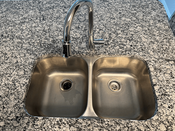 A stainless steel double sink with a chrome faucet.