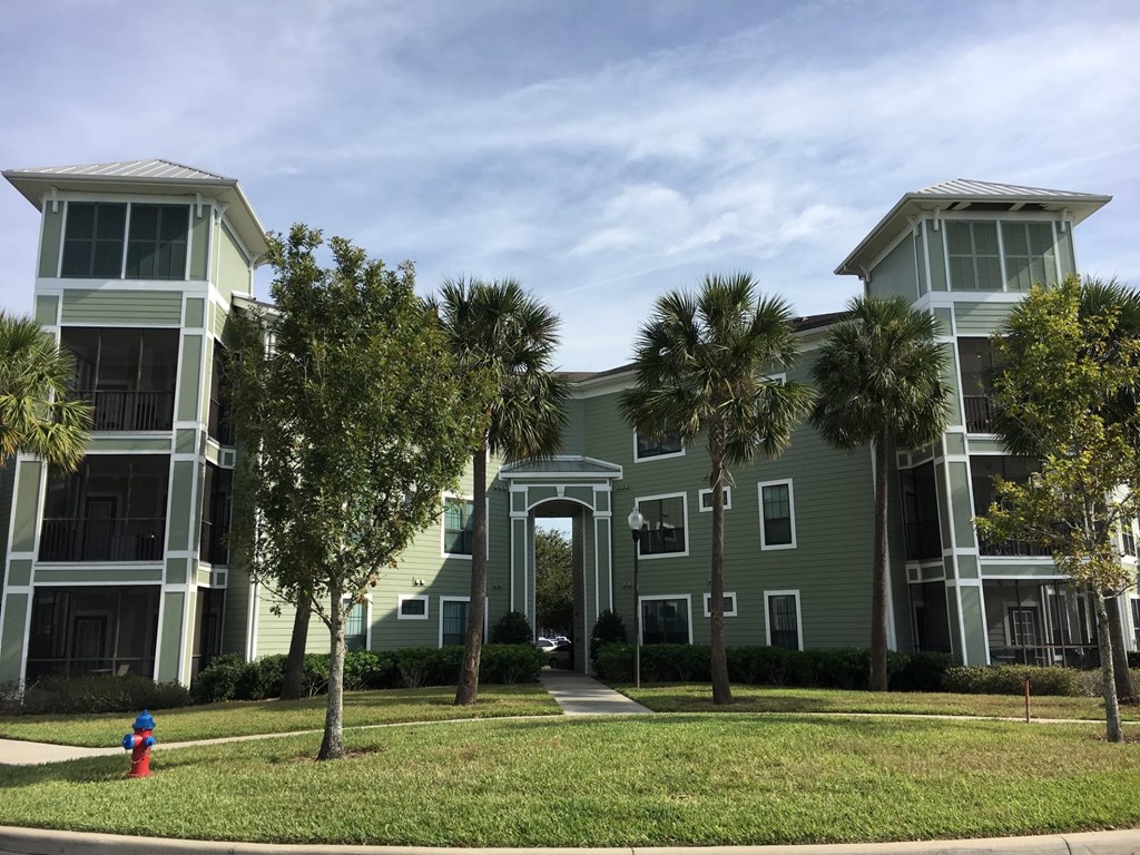 A fire hydrant is located on the grass in front of a building.