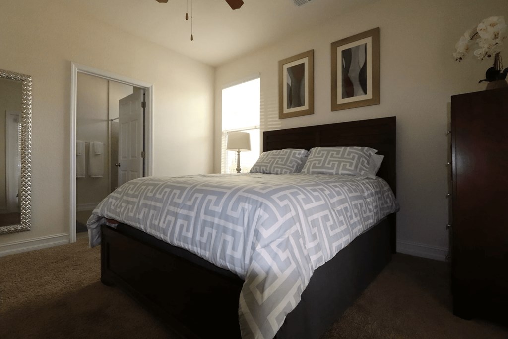 A bedroom with a bed, dresser, and mirror.