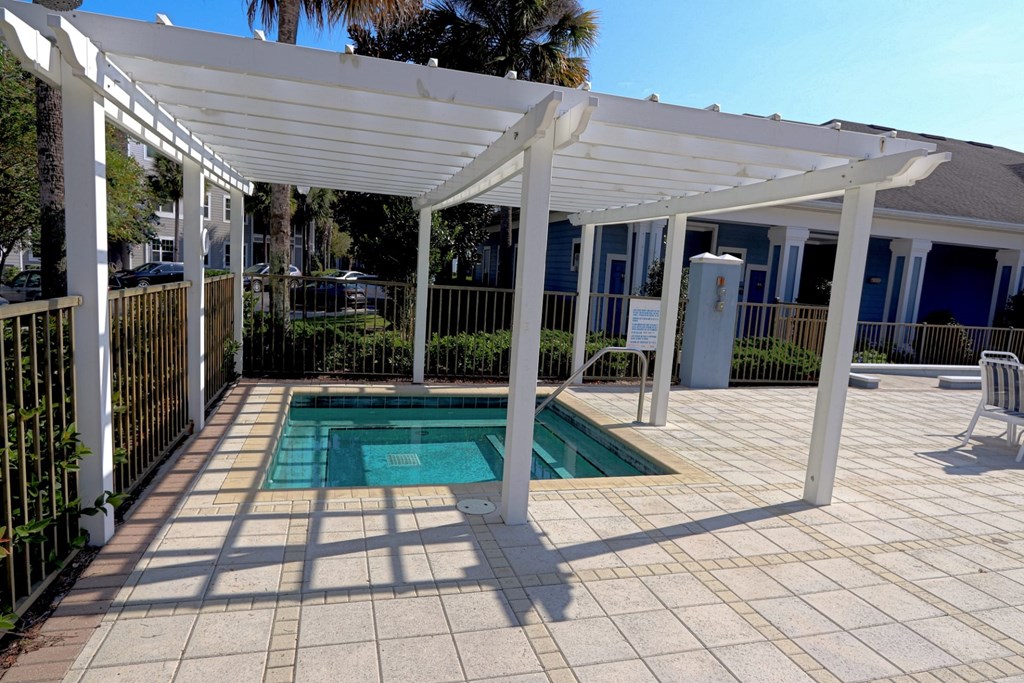 A pool under a white pergola on a sunny day.