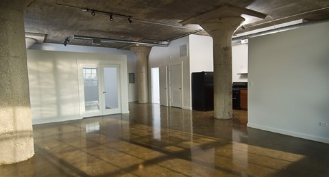 A large empty room with concrete pillars and a polished floor.