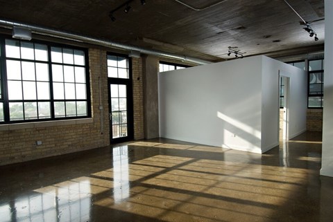 A large white box sits in a room with a brick wall and large windows.