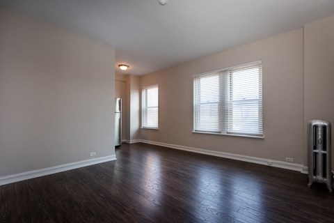 an empty living room with wood floors and a window