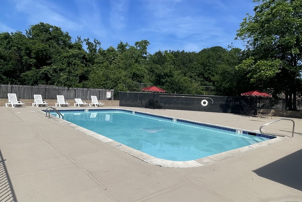 a swimming pool with chaise lounge chairs and trees in the background