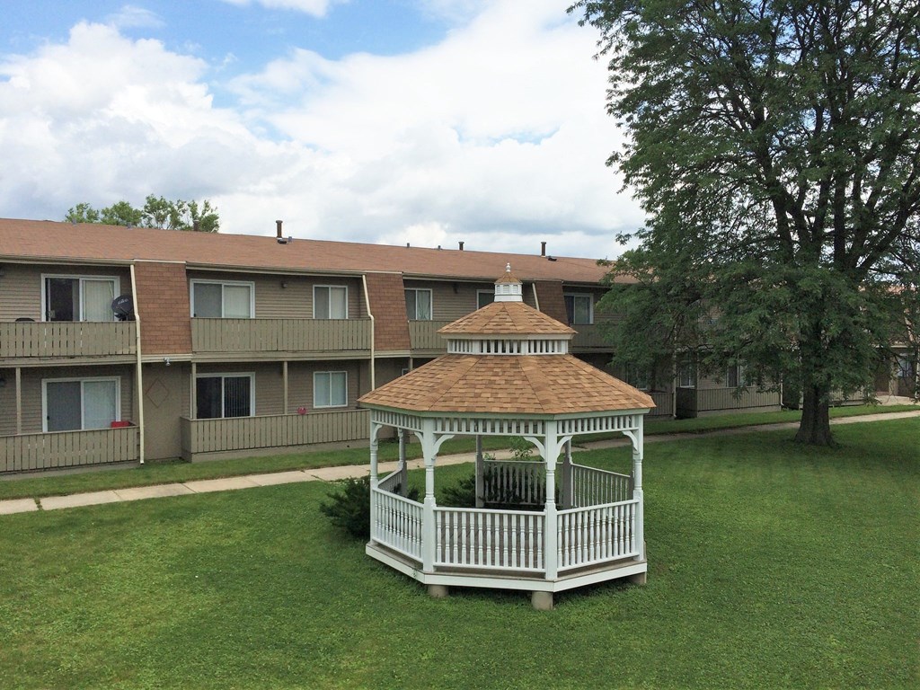 a gazebo in a yard in front of an apartment building