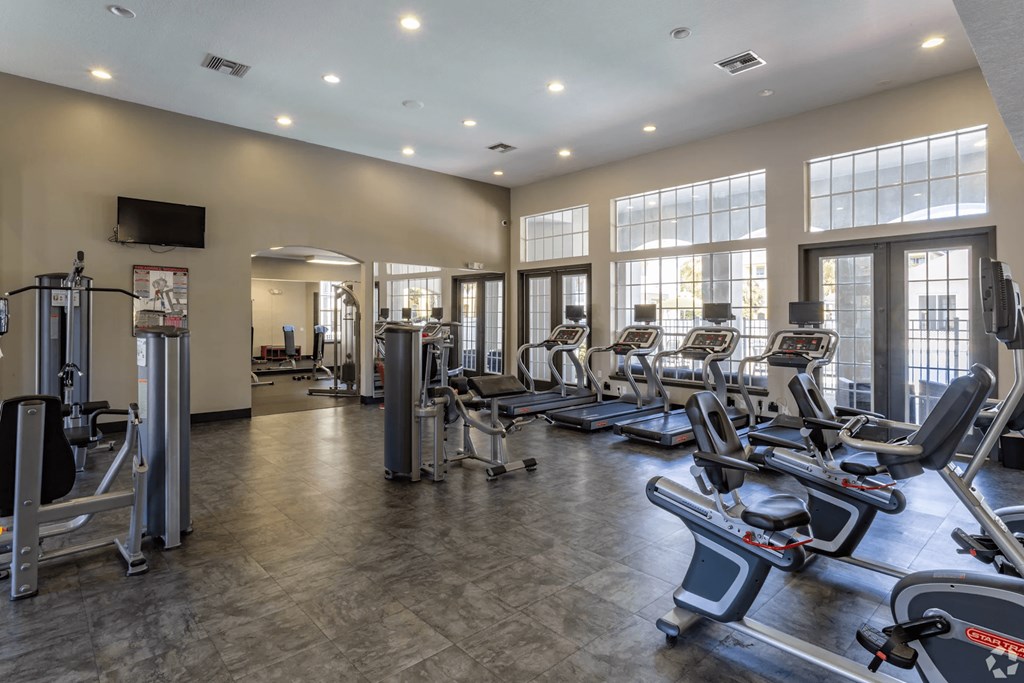 A gym with treadmills, elliptical machines, and a television.