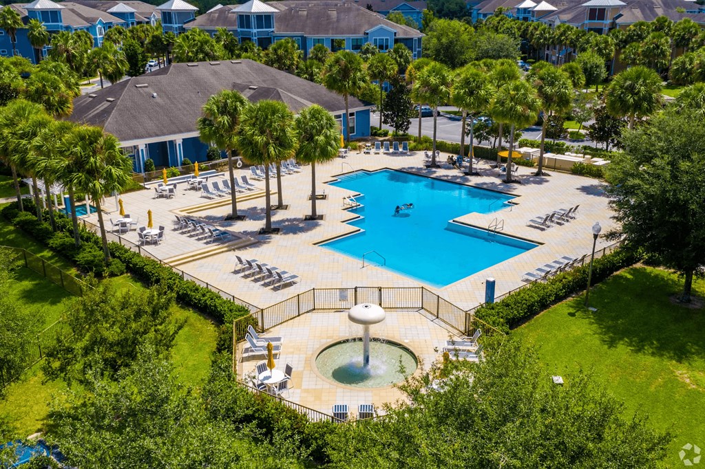 A large swimming pool surrounded by trees and a hot tub.