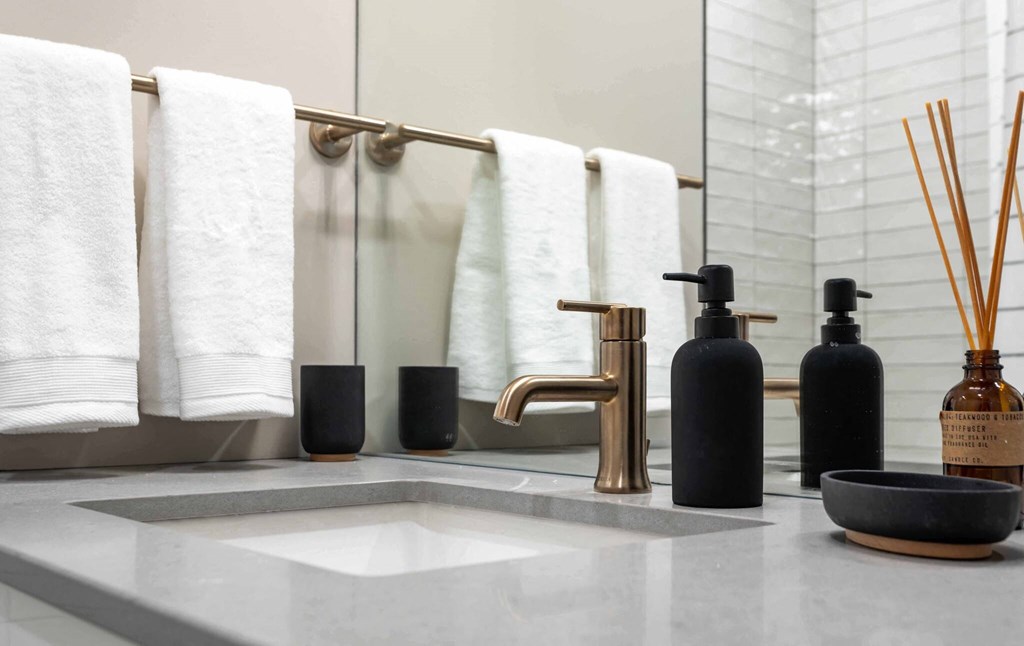 a bathroom with white towels and a sink and a brass faucet