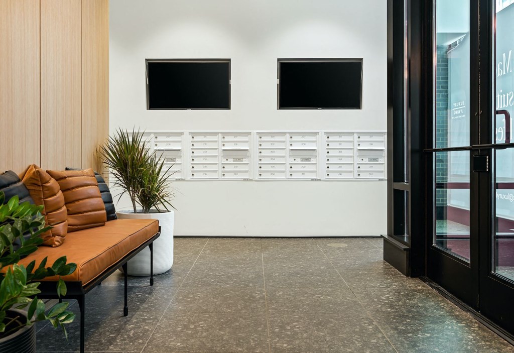a seating area with a couch and two televisions on the wall