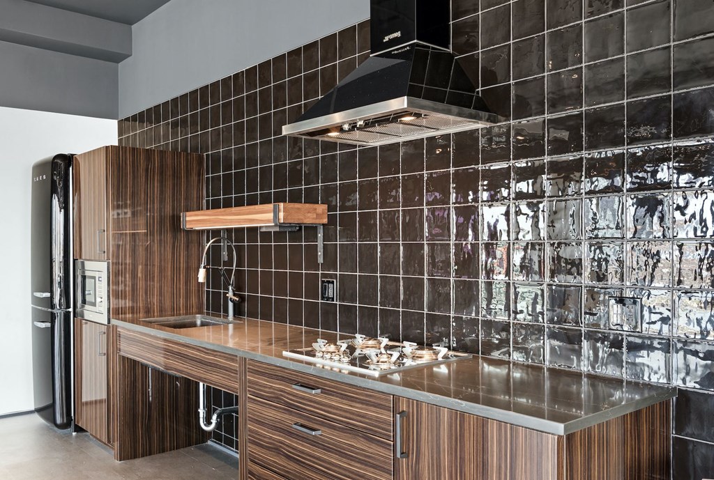 a kitchen with wooden cabinets and black tiles