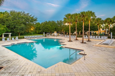 A large swimming pool surrounded by palm trees and lounge chairs.