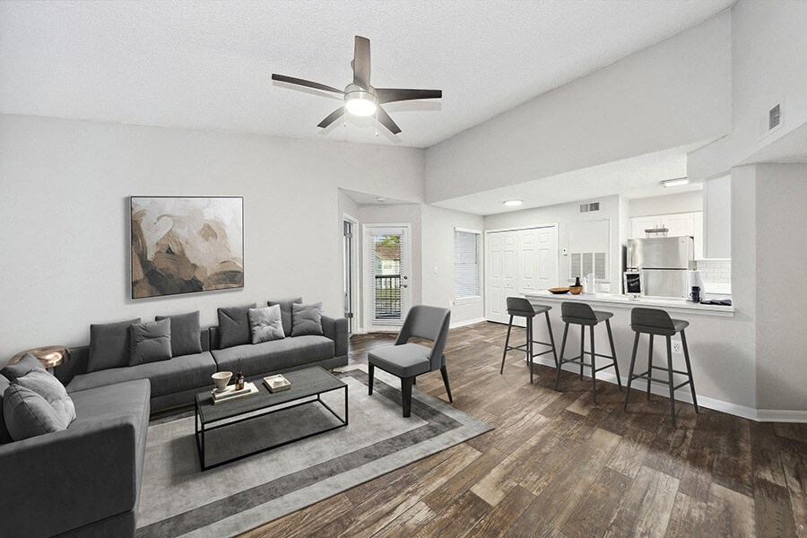 Model Living Room with Wood-Style Flooring and View of Kitchen at Retreat at Crosstown Apartments in Riverview, FL.