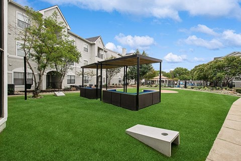 Outdoor Corn Hole Area and Lounge Furniture at Hidden Creek Apartments located in Lewisville, TX.