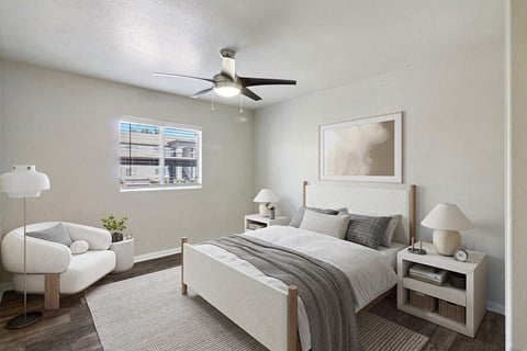 Las Vegas, NV, Apartments Near Nellis Air Force Base - Loma Vista - Bedroom With Upholstered Bed, Ceiling Fan With Light, Nightstands With Lamps, And A Large Window Over Plush Area Rug.