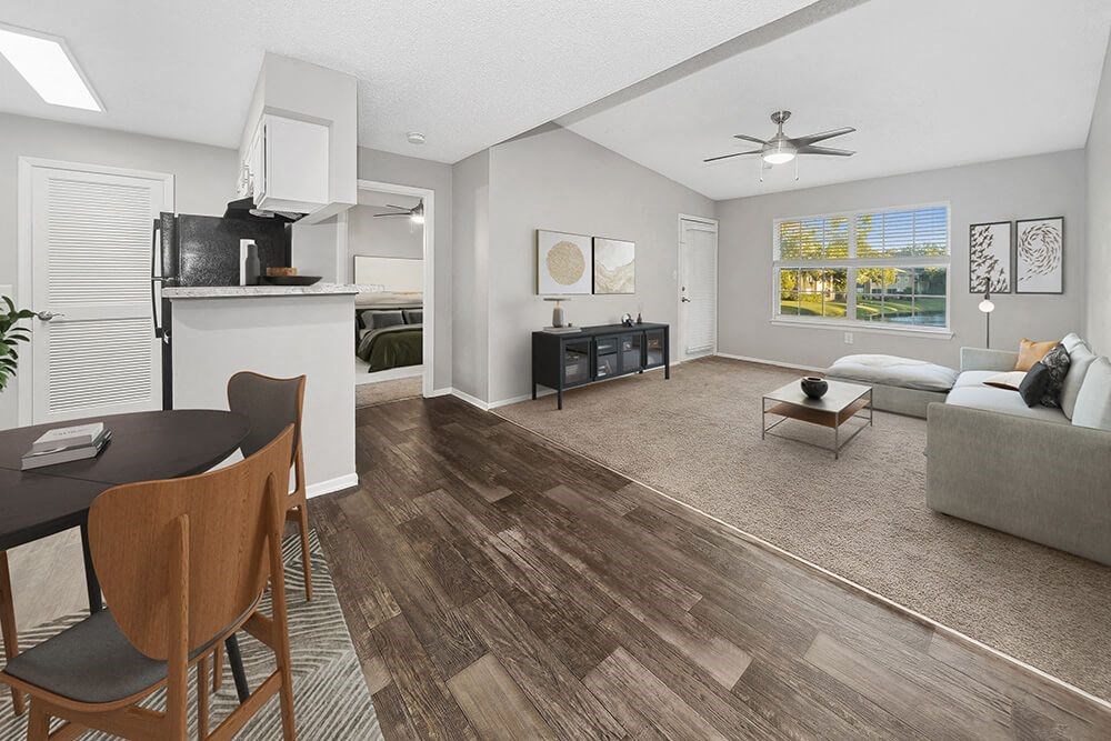 Model Dining Room and Kitchen Area with Wood-Style Flooring and View of Living Room at Walden Lake Apartments in Plant City, FL.