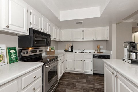 Model apartment kitchen with white cabinets and appliances