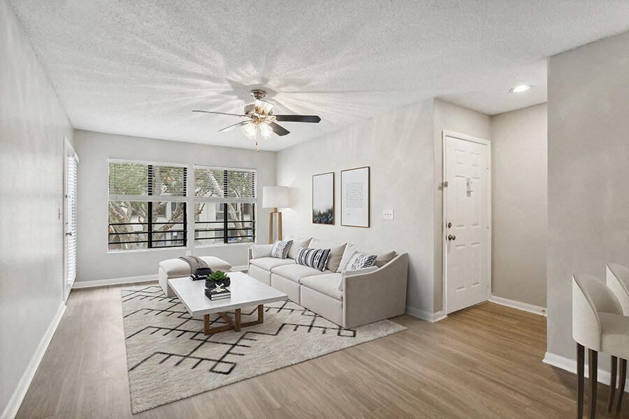 Model Living Room with Wood-Style Flooring and Patio Accessibility at Huntington Place Apartments located in Sarasota, FL.