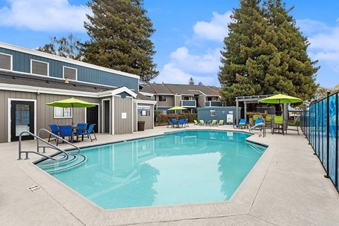 Apartments Near Touro University California in Vallejo, CA - The Meritage - Outdoor Swimming Pool With Sundeck, Lounge Chairs, Green Umbrellas, And Clubhouse Seating Area.