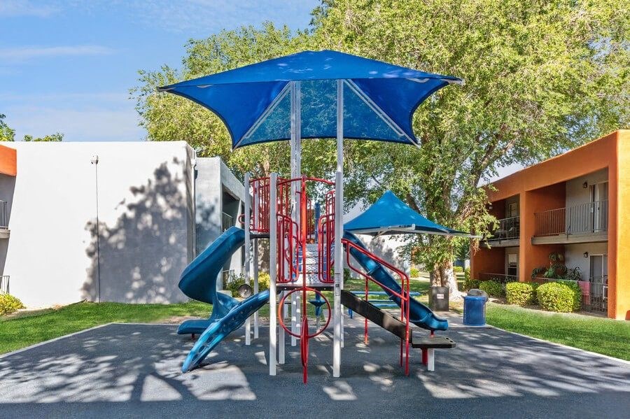 Community Playground with a Slide and Blue Canopy at Indigo Park Apartments in Albuquerque, NM.