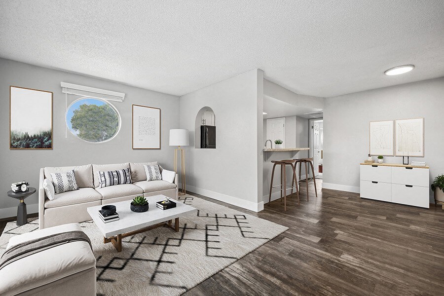 Model Living Room with Wood-Style Flooring and View of Kitchen at Stillwater Apartments located in Glendale, AZ.