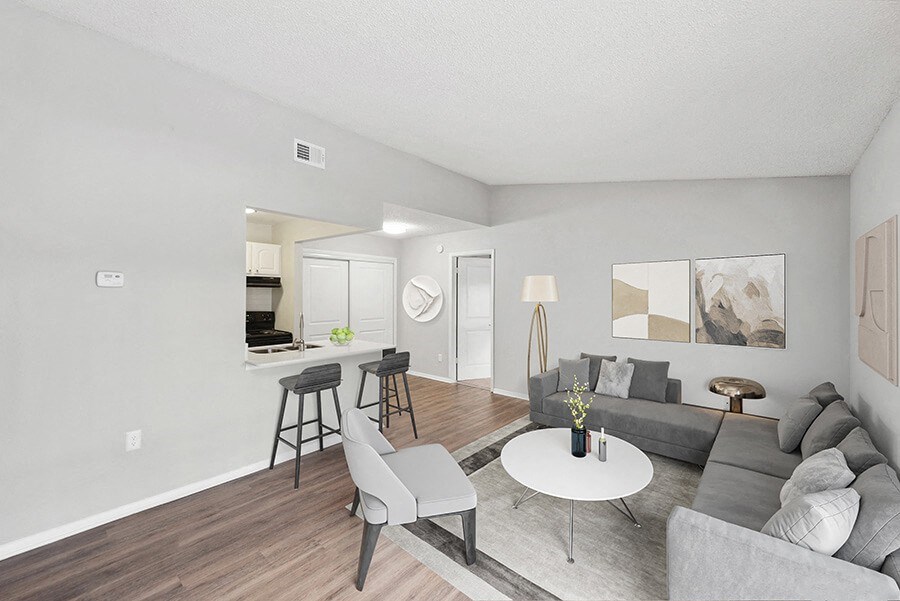 Model Living Room with Wood-Style Flooring and View of Kitchen at Vue at Baymeadows Apartments in Jacksonville, FL.