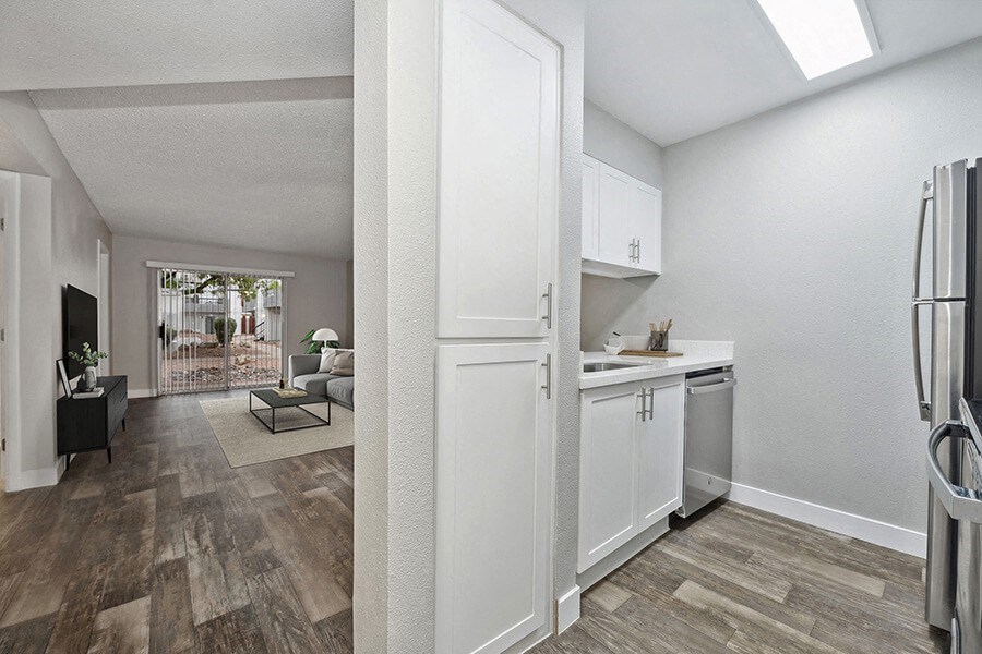 Model Kitchen with White Cabinets, Wood-Style Flooring and View of Living Room at Crystal Creek Apartments located in Phoenix, AZ.