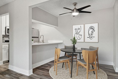 Model Dining Room with Wood-Style Flooring and View of Kitchen at Fullerton Hills Apartments located in Fullerton, CA.