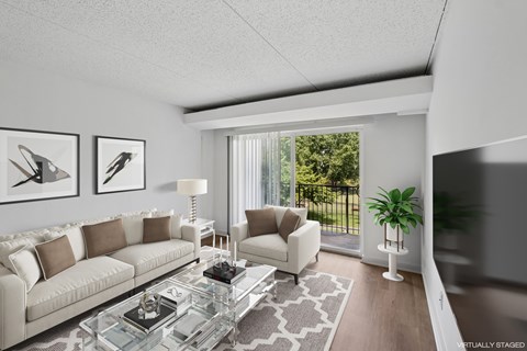 A modern living room with a glass coffee table and a large window.
