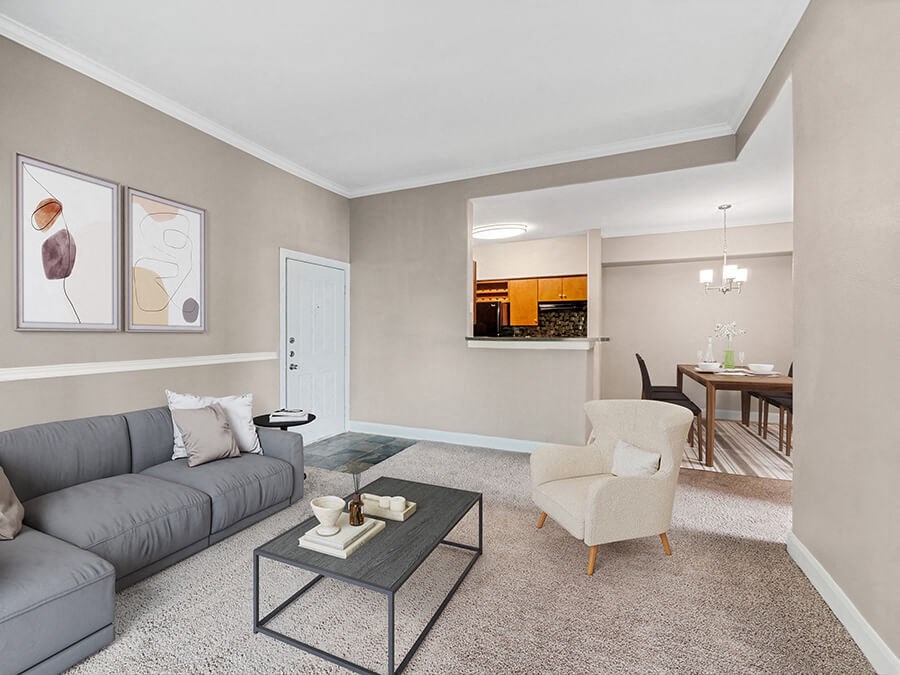 Model Living Room with Carpet and View of Kitchen/Dining Area at Park West Apartments located in Houston, TX.
