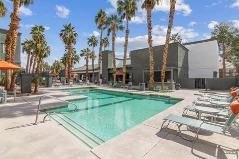 a swimming pool with palm trees and a building in the background