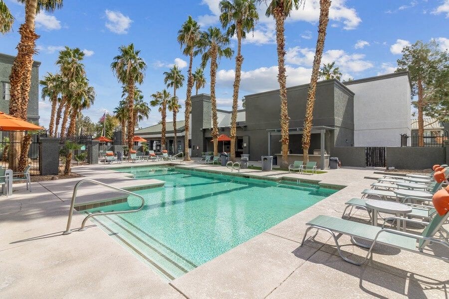 a swimming pool with palm trees and a building in the background