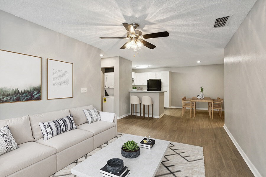 Model Living Room with Wood-Style Flooring and View of Dining/Kitchen Area at Huntington Place Apartments located in Sarasota, FL.