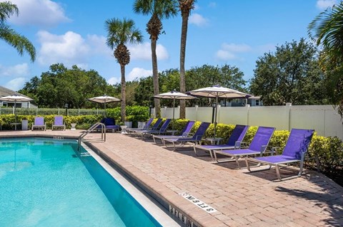 Community Swimming Pool with Pool Furniture at Waverley Place Apartments in Naples, FL.