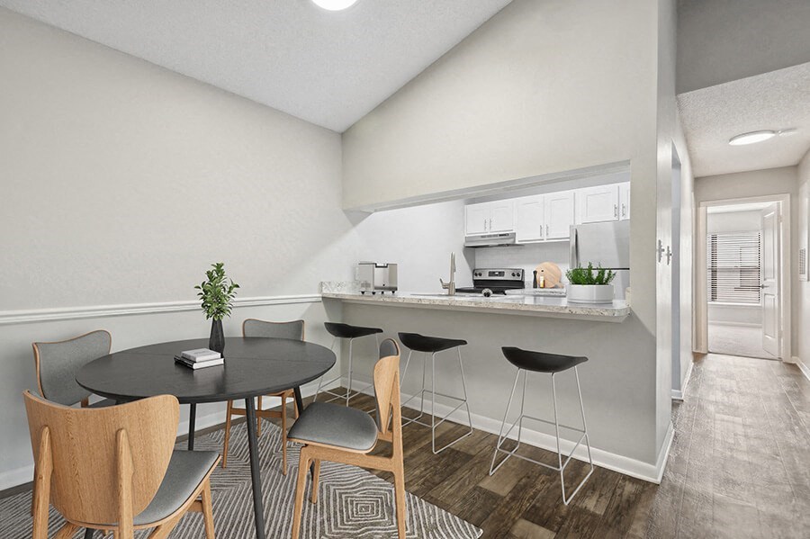 Model Dining Room and Kitchen with Wood-Style Flooring and Hallway View at Rosehill Preserve Apartments located in Orlando, FL.