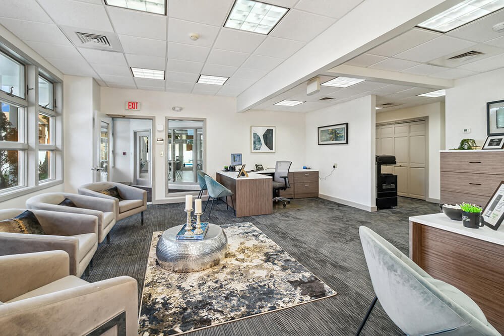 Leasing office interior with couches and chairs and a coffee table in the middle of the room