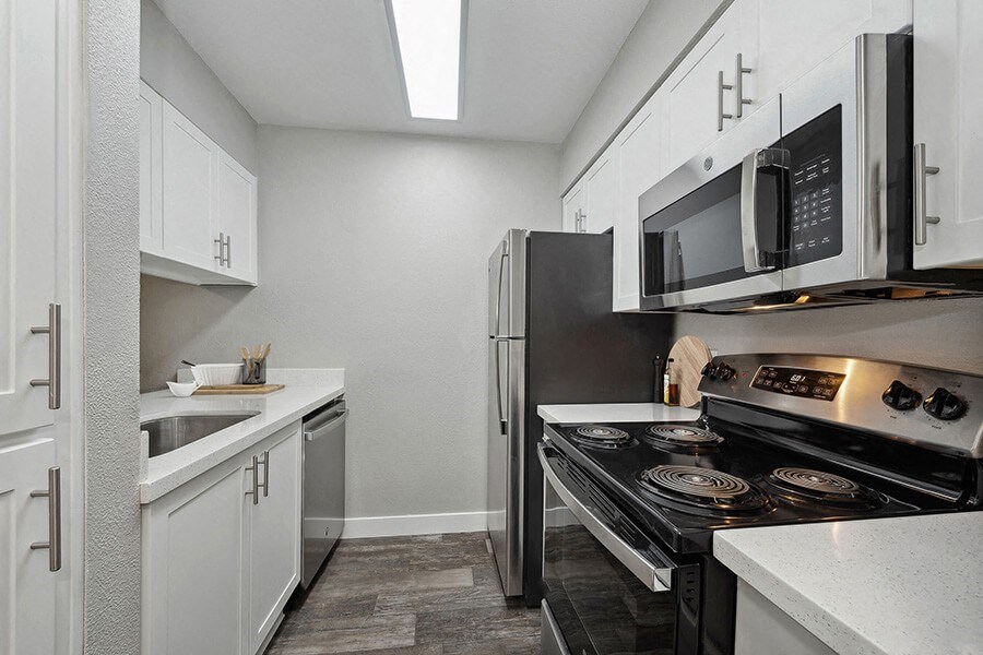 Model Kitchen with White Cabinets and Wood-Style Flooring at Crystal Creek Apartments located in Phoenix, AZ.