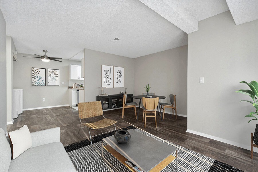 Model Living Room with Wood-Style Flooring and View of Kitchen/Dining Area at Liberty Creek Apartments in Aurora, CO.