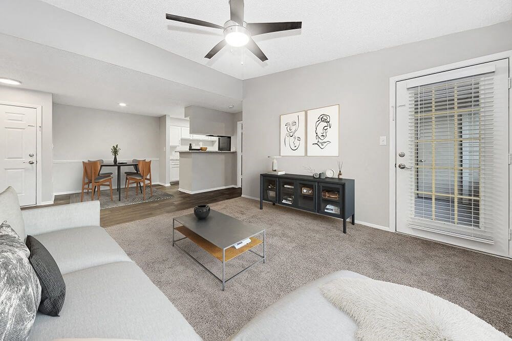Model Living Room with Carpet, Patio Accessibility and View of Kitchen/Dining Area at Walden Lake Apartments in Plant City, FL.
