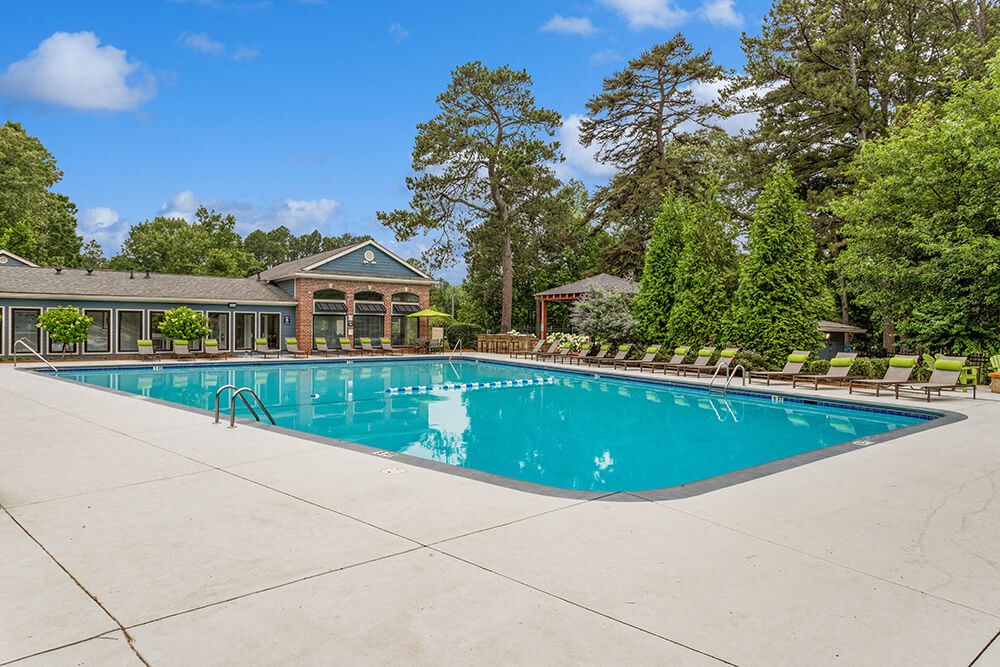 Resort-style swimming pool with lounge chairs and trees in the background