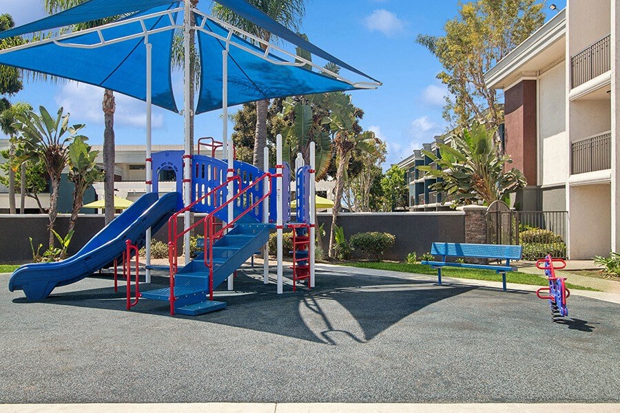 Community Playground with Slide and Blue Canopy at Madison Park Apartments located in Anaheim, CA.