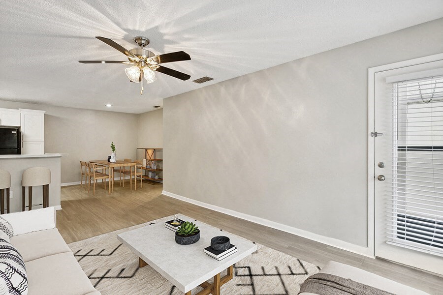 Model Living Room with Wood-Style Flooring and Patio Accessibility at Huntington Place Apartments located in Sarasota, FL.