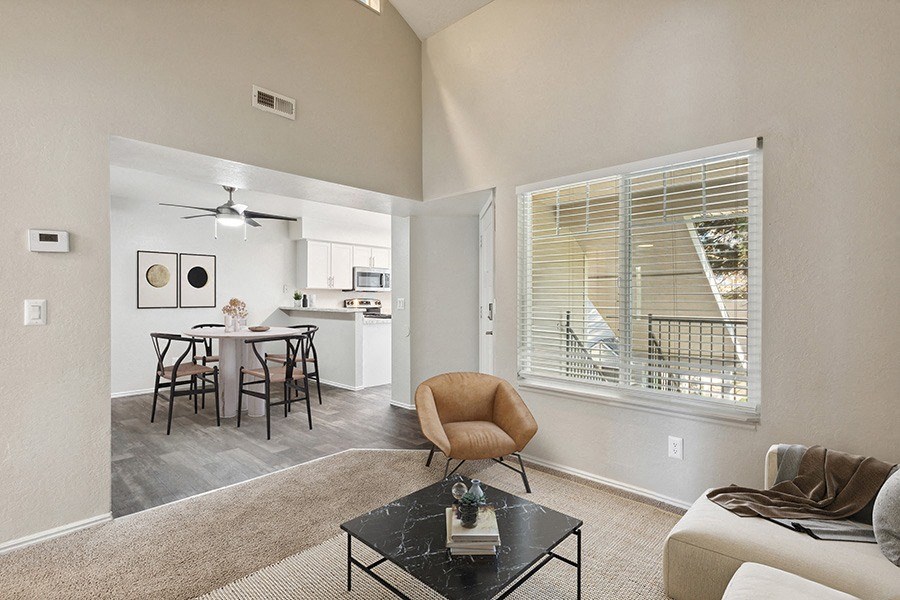 Model Living Room with Carpet and View of Kitchen/Dining Area with Wood-Style Flooring at Broadmoor Village Apartments in Salt Lake City, UT.
