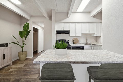 a white kitchen with a marble counter top and a table