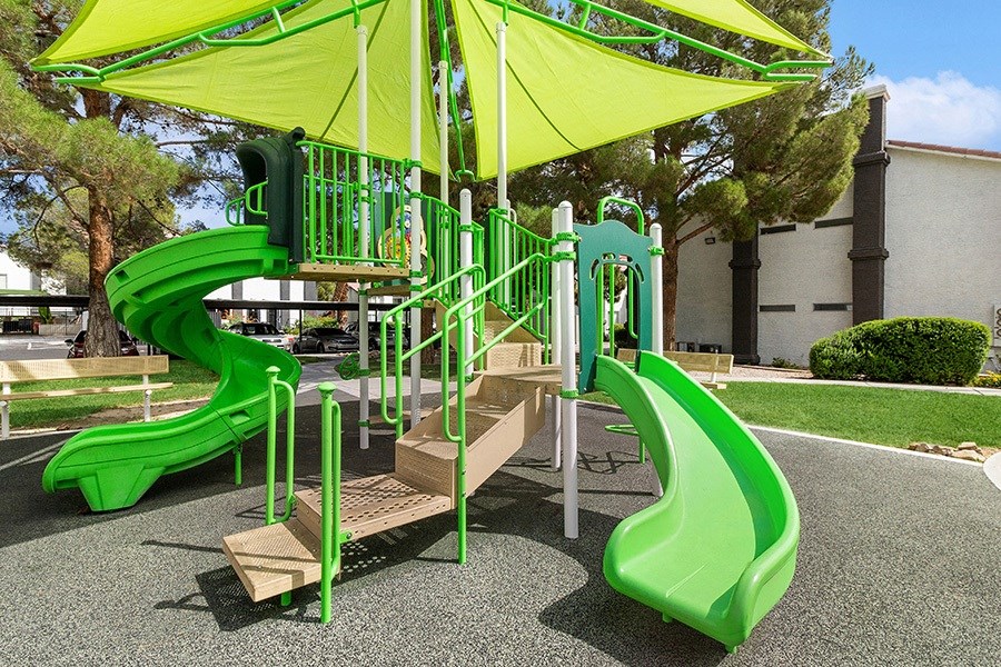 Community Playground with two Slides and a Green Canopy at Meadow Ridge Apartments in Las Vegas, NV.