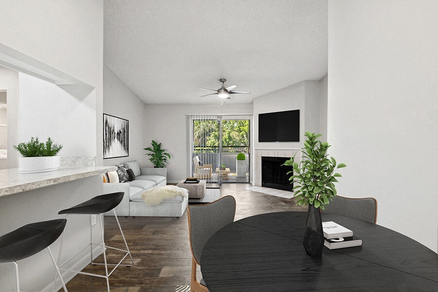 Model Dining Room with Wood-Style Flooring and View of Living Room with Fireplace at Rosehill Preserve Apartments located in Orlando, FL.
