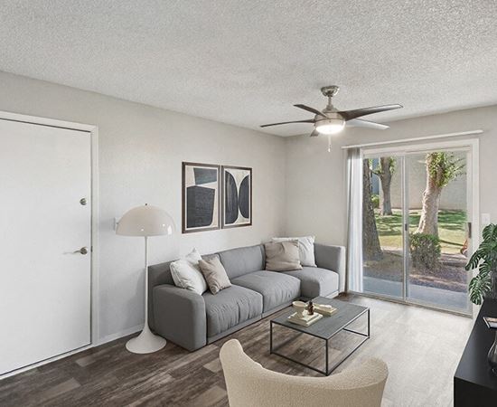 Apartments in South Tucson, AZ - Solano Springs - A Living Room With A Gray Sofa, Coffee Table, Ceiling Fan, Floor Lamp, And Sliding Glass Doors.